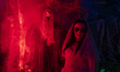 A young woman characterized as a corpse bride poses on a stage with terrifying lighting in...