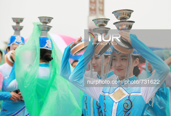 ORDOS, Aug 13, 2015 () -- Mongolian dancers use their property props to protect themselves from the rain during a performance gala by all th...