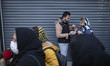 An Iranian couple eat meal while standing on a street-side in downtown Tehran, amid the CO...
