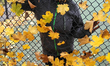 Woman poses by leaves blown against a chain-link fence during the Autumn season in Toronto...