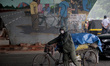 A trolley rickshaw puller wears protective mask as he is seen at the daily market area and...
