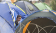 A migrant woman poses as she and other migrants wait on the Macedonian-Greek border where...