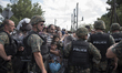 A young migrant looks through the cordon of police, where they are waiting on the Macedoni...