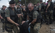 A young migrant woman faints after waiting on the Macedonian-Greek border where migrants a...