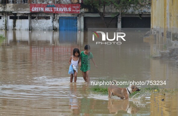 Two kids along with their peg dog wade through flooded street after heavy downpour in Dimapur, India north eastern state of Nagaland on Thur...