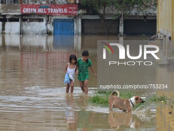 Two kids along with their peg dog wade through flooded street after heavy downpour in Dimapur, India north eastern state of Nagaland on Thur...