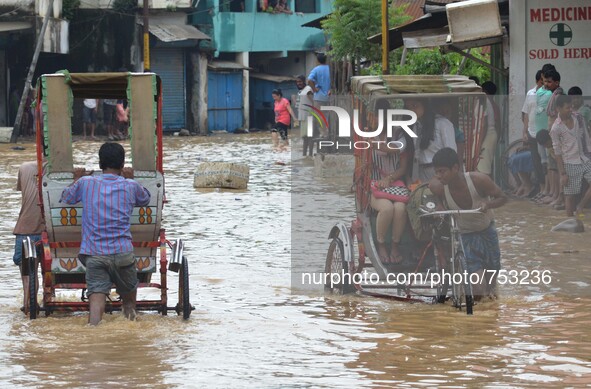 Indian rickshaw puller pulls commuters to higher ground in a flooded street after heavy downpour in Dimapur, India north eastern state of Na...