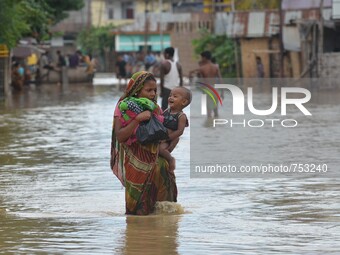 An Indian woman carries her child as they wade through flooded street after heavy downpour in Dimapur, India north eastern state of Nagaland...