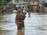 An Indian woman carries her child as they wade through flooded street after heavy downpour in Dimapur, India north eastern state of Nagaland...