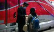 Employee help a traveller past the first Frecciarossa, a high-speed train of the Italian n...