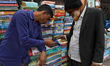 Booksellers play games on mobile a phone at a roadside second-hand bookshop in Dhaka, Bang...