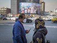 An Iranian couple talk to each other as a giant billboard with a symbolic portrait of the Iranian top military officer general Qasem Soleima...