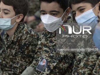 Iranian young boys in military uniforms wearing protective face masks as one of them pastes a portrait of the Iranian top IRGC commander, Ge...
