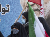 Iranian veiled women carrying Iran flags as they walk past a portrait of the Iranian top IRGC commander, General Qasem Soleimani who was kil...