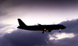 Silhouette of a landing aircraft with a cloudy background after the sunset. The passenger...