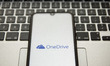 In this photo illustration an OneDrive logo seen displayed on a smartphone screen with a c...