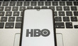 In this photo illustration a HBO logo seen displayed on a smartphone screen with a compute...