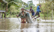 An Indian man wade through flood waters as flash flood hit the region at Naharkatia, about...