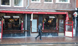 Daily life in Amsterdam with people passing in front of closed cafe, bars and restaurants....