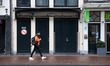 Daily life in Amsterdam with people passing in front of closed cafe, bars and restaurants....
