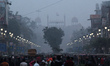 People shop at a crowded market on a foggy winter evening, in front of the Red Fort in the...