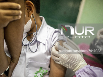 A student holds his father's hand before receiving an injection of the COVID-19 vaccine in South Tangerang, Banten, Indonesia on 17 January...
