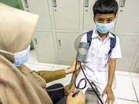 A student has his blood pressure checked before receiving the COVID-19 vaccine in South Tangerang, Banten, Indonesia on 17 January 2022. Ind...