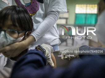 A student holds his mother's hand tightly while receiving an injection of the COVID-19 vaccine in South Tangerang, Banten, Indonesia on 17 J...