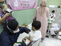 A mother records the process of her child's covid-19 vaccine in South Tangerang, Banten, Indonesia on 17 January 2022. Indonesia is preparin...