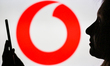An image of a woman holding a cell phone in front of the Vodafone logo displayed on a comp...