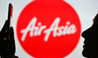 An image of a woman holding a cell phone in front of the AirAsia logo displayed on a compu...