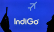 An image of a woman holding a cell phone in front of the IndiGo Airline logo displayed on...