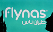 An image of a woman holding a cell phone in front of the FlynasDomestic airline logo disp...