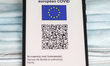 EU Digital COVID Certificate is displayed on a mobile phone screen photographed on surgica...