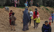 Palestinian children wait with their pots to recieve free food cooked by Amel Abu Amra (un...