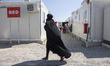 A young woman as seen walking in the camp wearing the traditional muslim abaya. Inside the...