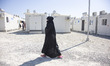 A young woman as seen walking in the camp wearing the traditional muslim abaya. Inside the...