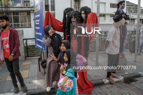 Woman is seen taking a picture with cosplayer as ghost costume near Gedung Merdeka on January 29, 2022 in Bandung, Indonesia. Based on data...