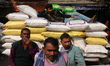 Labourers rest on top of sacks with goods ready for transportation at a busy wholesale mar...