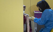 An Iranian woman wearing a protective face mask receives a dose of the new coronavirus dis...
