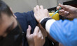An Iranian man wearing a protective face mask receives a dose of the new coronavirus disea...