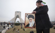 An Iranian man holds a portrait of Iran’s Supreme Leader Ayatollah Ali Khamenei while stan...