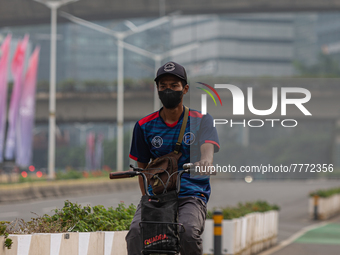 Man wear protective face masks rides bicycle in business district in Jakarta on February 14, 2022. The Minister of Manpower, Ida Fauziyah, s...