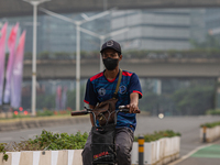 Man wear protective face masks rides bicycle in business district in Jakarta on February 14, 2022. The Minister of Manpower, Ida Fauziyah, s...
