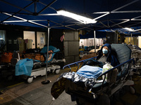A patient lies in a hospital bed waiting for medical treatment in a temporary holding area outside Caritas Medical Center in Hong Kong, Chin...