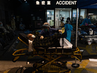 A patient lies in a hospital bed waiting for medical treatment in a temporary holding area outside Caritas Medical Center in Hong Kong, Chin...