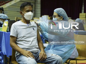 People receive doses of the Pfizer COVID-19 vaccine at a vaccination center inside a stadium in Bangkok, Thailand, 24 February 2022. (