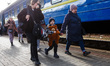 People evacuated from Ukrainian cities under fire from the Russian army walk to  board a t...