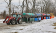 Visitors ride in cars attached to a tractor to take them to the sugarbush at a maple syrup...