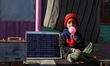 Misba, fills air in a balloon as she sits near a Home solar panel in a far flung Area Of K...